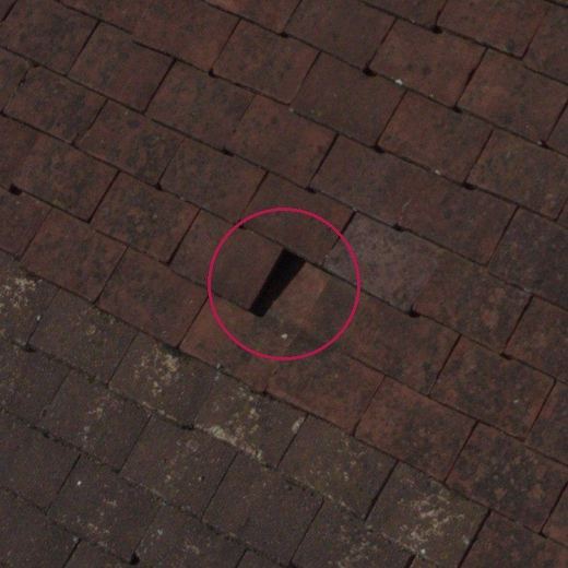 Close-up of a slipped tile leaving an open slot in the roof, circled